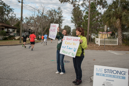 Team Mainstreet cheering on runners with handmade signs with motivational sayings.