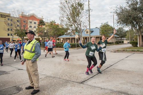 Members of Team Mainstreet smiling and waving at an early part of the MeStrong 5k race in DeLand