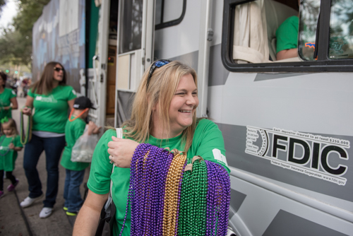 A member of Team Mainstreet laughing with an arm full of Mardi Gras beads for the dog parade in DeLand