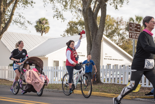 One of the founders of MeStrong riding her bike while cheering on runners with a bullhorn