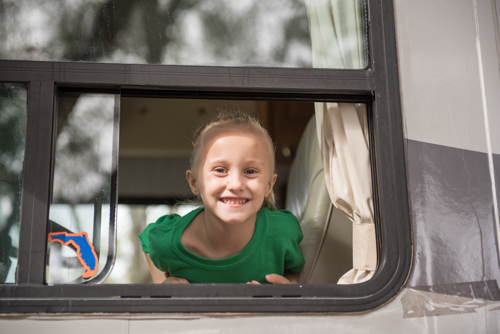 A little girl smiling from the window of the Mainstreet Community Bank RV before the Mardi Gras on Mainstreet Parade