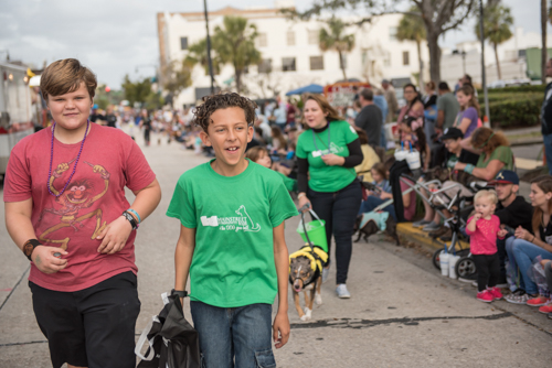 Two boys smiling while walking in the Mardi Gras dog parade in DeLand