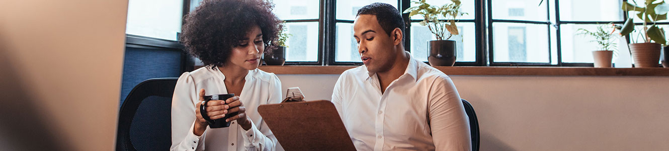 A woman and a man looking at a clipboard.
