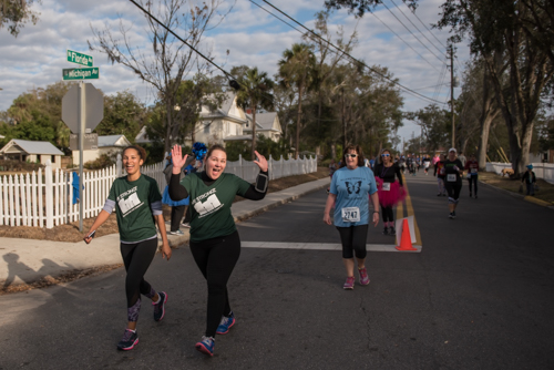 Members of Team Mainstreet smiling and waving while running in the MeStrong 5k race in DeLand