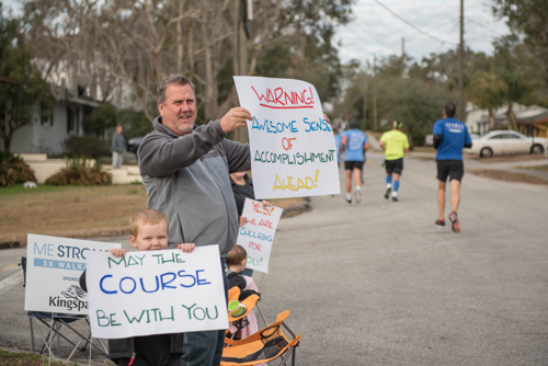 Family members of Mainstreet employees cheering on runners with handmade signs with motivational sayings.