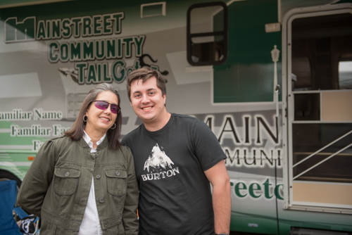 Mother and adult son posing for photo in front of Mainstreet Community Bank RV at Pig on the Pond