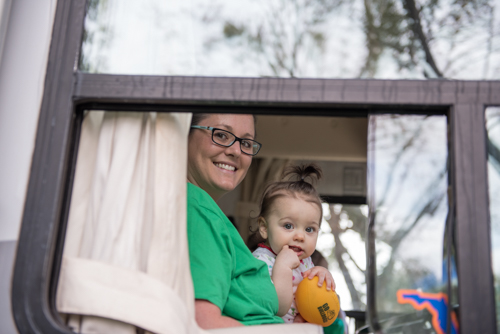 A mom and her daughter smiling from the window of the Mainstreet Community Bank RV before the Mardi Gras dog parade in DeLand