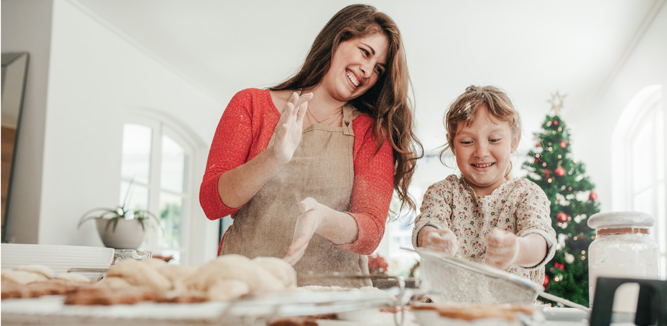 Mother and child decorating cookies with Christmas Tree in background
