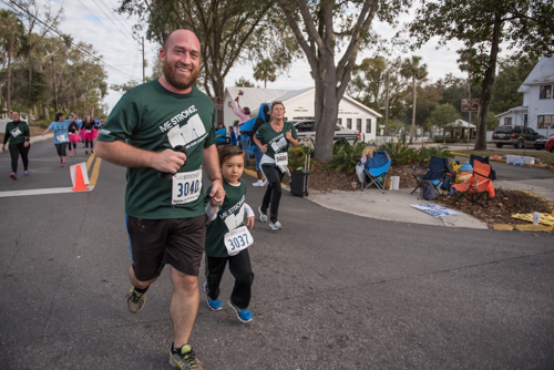 Members of Team Mainstreet smiling while running in the MeStrong 5k race in DeLand
