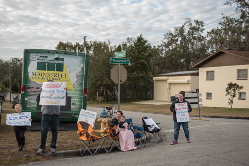 Team Mainstreet cheering on runners with handmade signs with motivational sayings in front of the Mainstreet RV during MeStrong 5k.