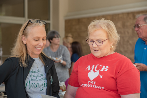 Two Mainstreet team members chat while customers gather in background