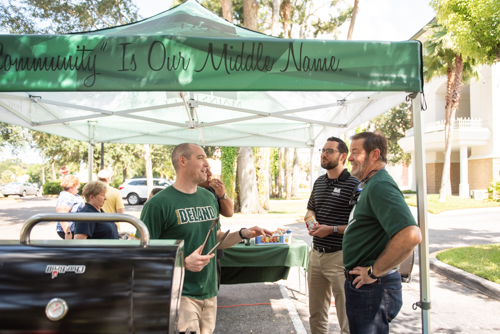 Three men talk while grilling food at customer appreciation day in DeLand
