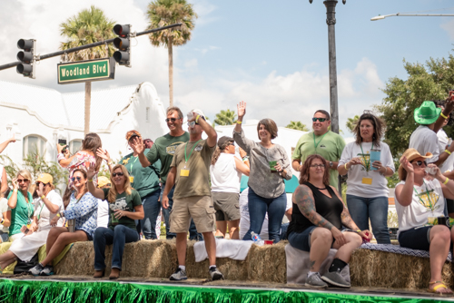 A float full of people wave at crowds during parade