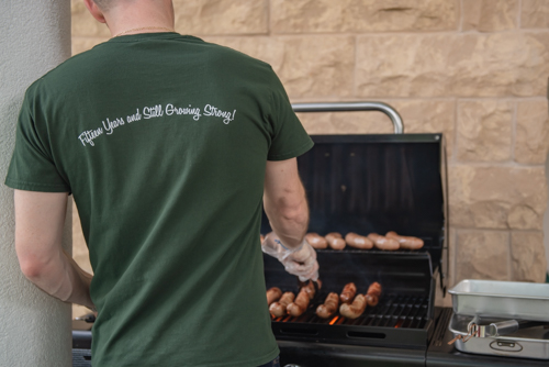 A Mainstreet Team member cooks hot dogs on a grill during Customer Appreciation in downtown DeLand