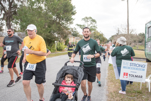 Member of team Mainstreet running MeStrong with daughter in stroller.