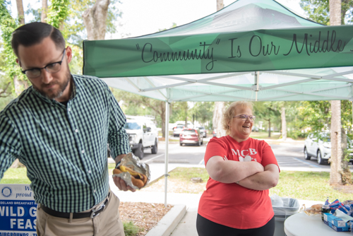A Mainstreet team member laughs while a man prepares a hot dog during Customer Appreciation in DeLand