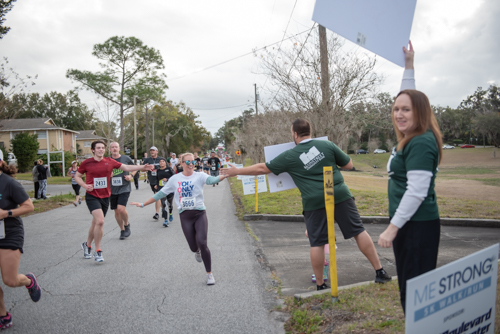 Runners high fiving Team Mainstreet members at a cheering station along MeStrong route