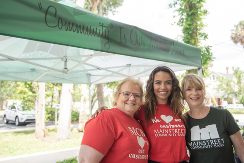 Three employees smiling while preparing for Customer Appreciation Day at Mainstreet Community Bank