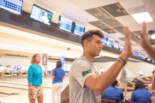 Man gives high five after his turn at bowling alley