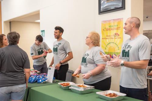 Members of Team Mainstreet smile and laugh as they chat with teachers during lunch at DeLand High School