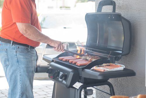 Hot dogs and brats cook over an open flame on a grill at Customer Appreciation Day for Mainstreet Community Bank