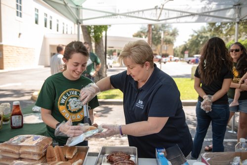 Team members prepare hot dogs for customers during customer appreciation day