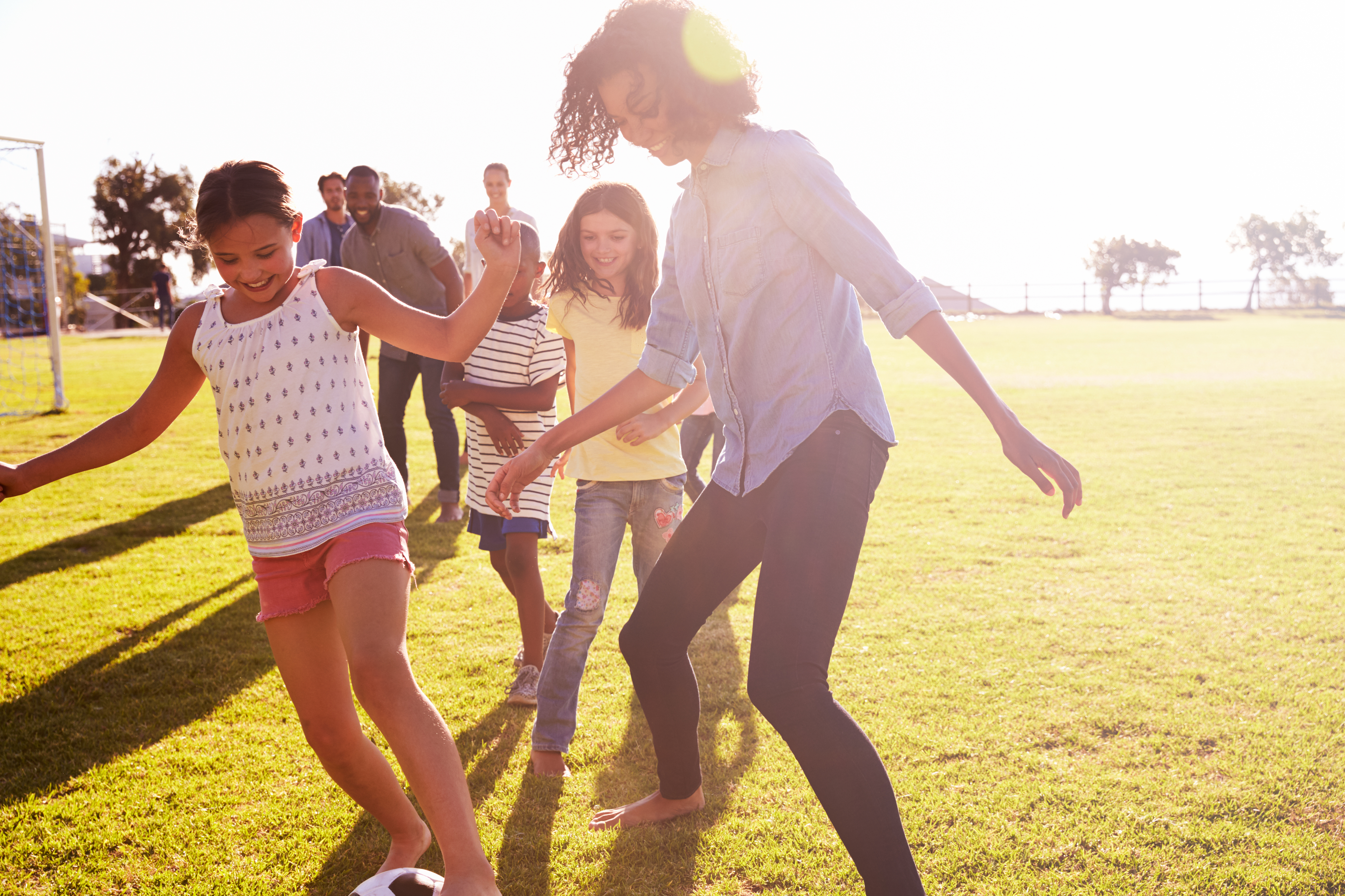 Woman and three children playing soccer.