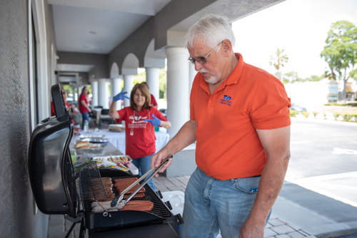 A Mainstreet team member grills hot dogs and brats on the grill before Customer Appreciation Day.