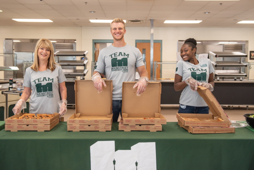 Two women and a man smile while waiting for teachers to arrive for lunch at DeLand High School cafeteria